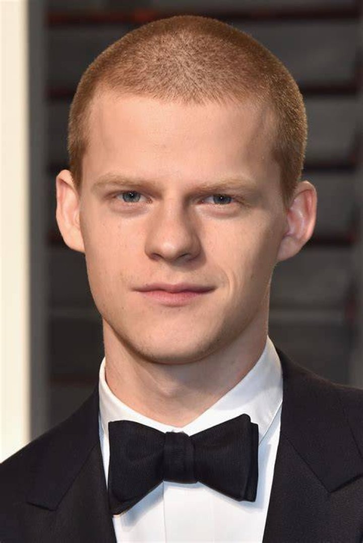 Lucas Hedges in a blue shirt and ginger hair while posing for the camera