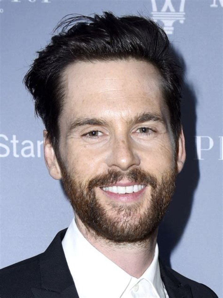 Tom Riley in a black-and-white car-selfie with his dog in the background in September 2018